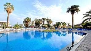 A swimming pool with lounge chairs and palm trees. - BLUESEA Interpalace (Puerto de la Cruz)