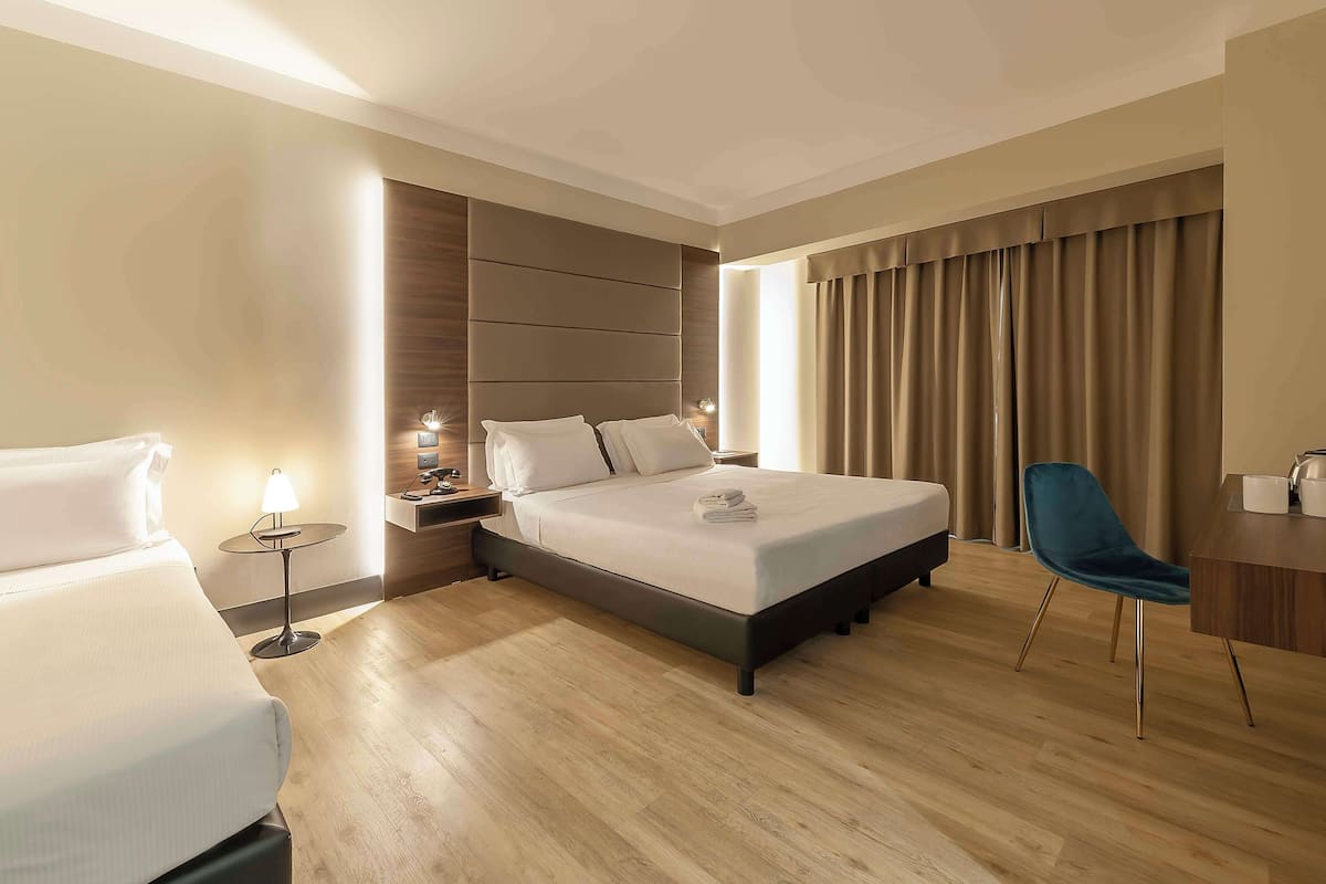 Une chambre d’hôtel moderne, dotée d’un grand lit, de tables de chevet, d’un bureau et d’une chaise.