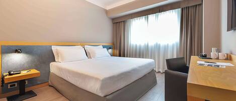 Una habitación de hotel con cama, escritorio, silla y televisor.