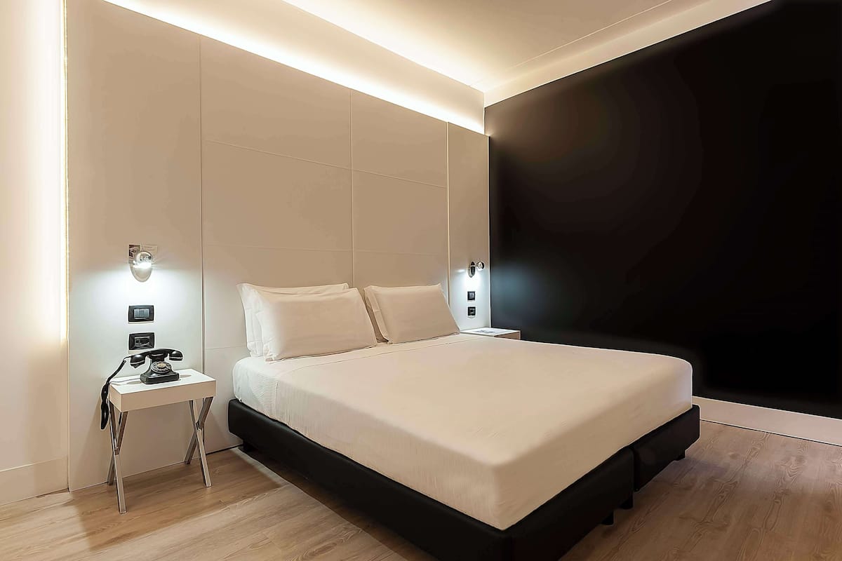 Une chambre moderne avec un grand lit, des tables de chevet et un mur d’accent de couleur foncée.