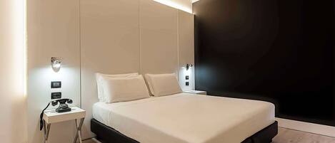 Un dormitorio moderno con una cama grande, mesitas de noche y una pared de acento oscura.