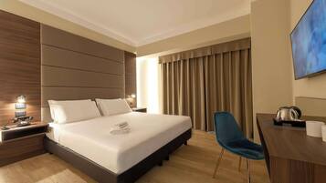 Habitación de hotel moderna con una cama grande, un escritorio, una silla y un televisor de pantalla plana.