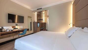 Una habitación de hotel moderna con una cama grande, un escritorio con silla, un televisor de pantalla plana y un vestidor.