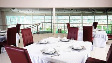 A restaurant with tables set for dining, large windows, and a view of the city.