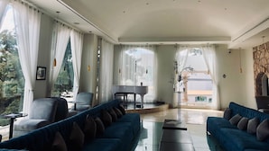 Un amplio salón con un piano, dos sofás y una mesa de comedor.