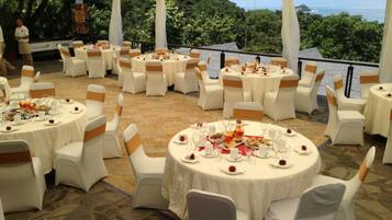 An outdoor dining area with round tables and white chairs, set up for a formal event.