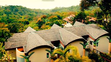 A row of houses with curved roofs, surrounded by lush greenery and hills.