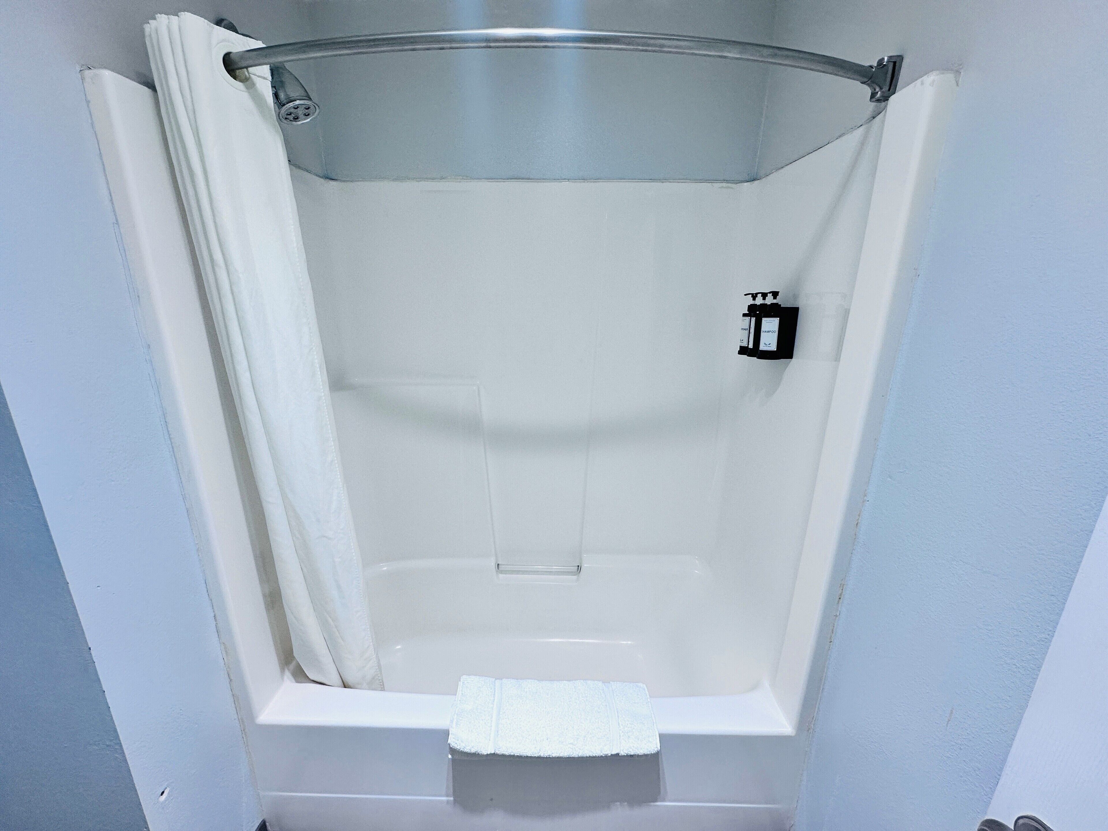 A small, enclosed shower area with a white towel on the floor.