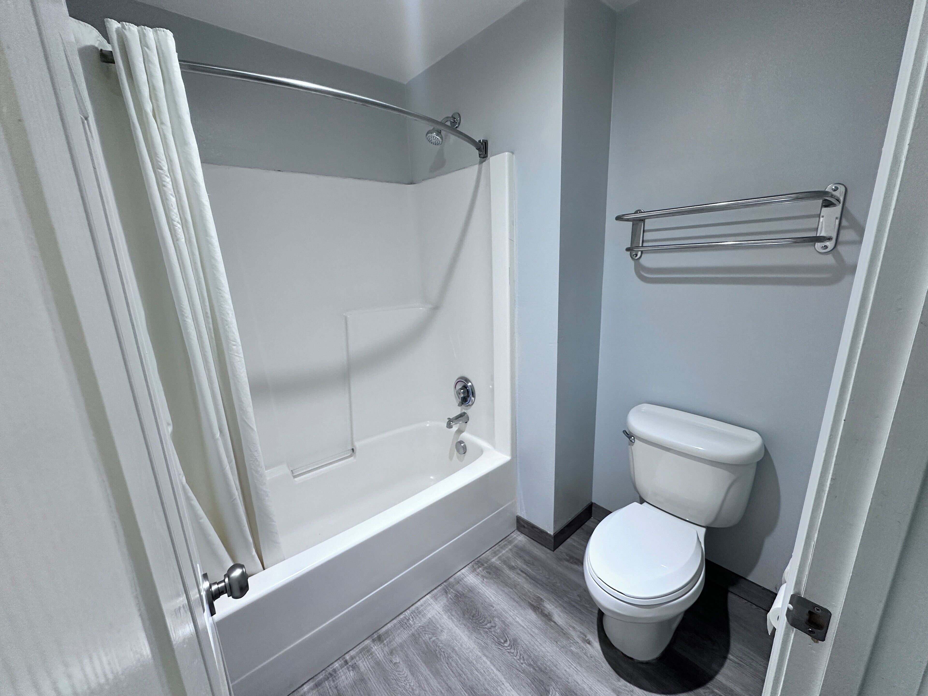 A bathroom with a bathtub, toilet, and a towel rack.