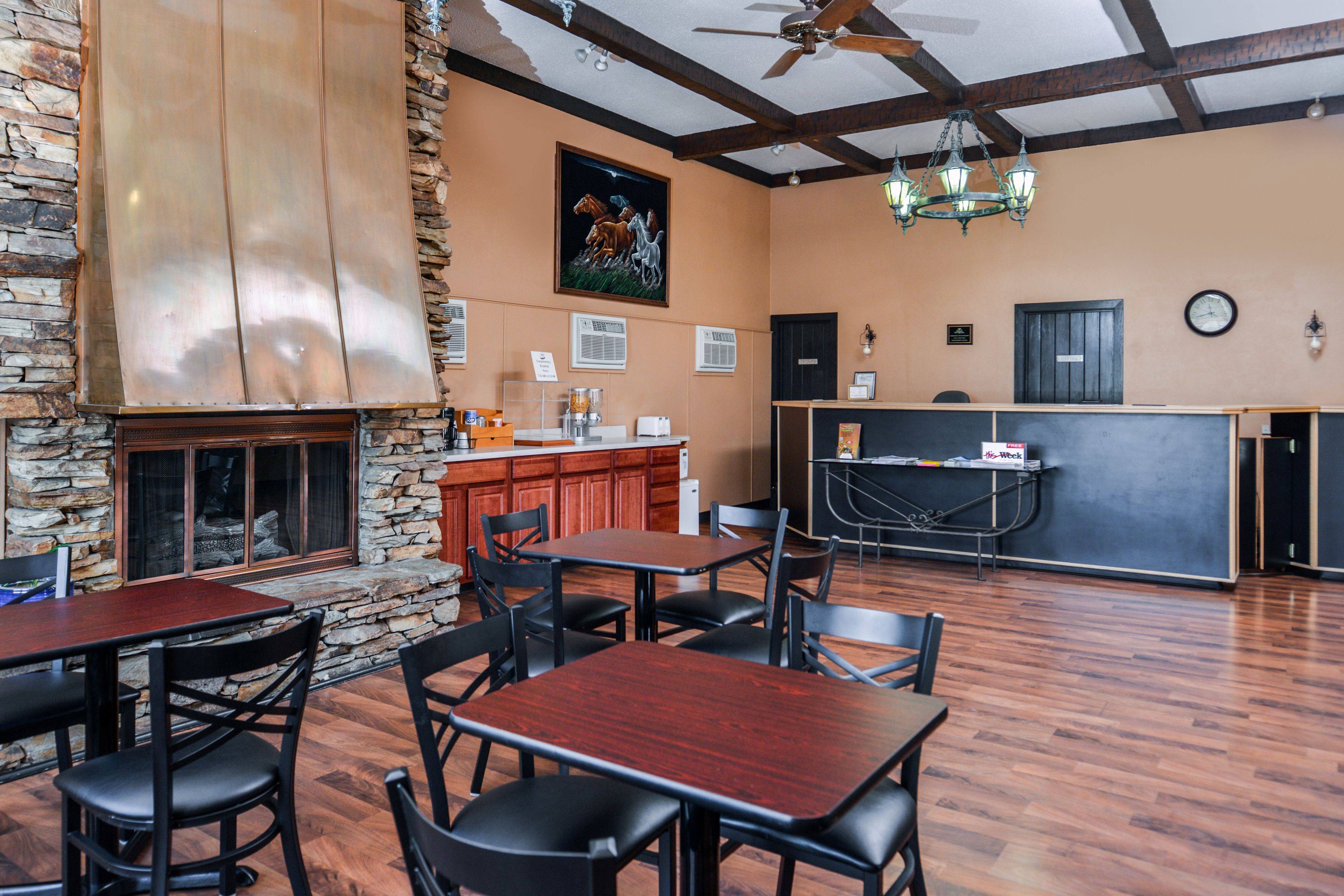 A restaurant with stone walls, wooden tables, and chairs. There is a bar area with a counter and stools.