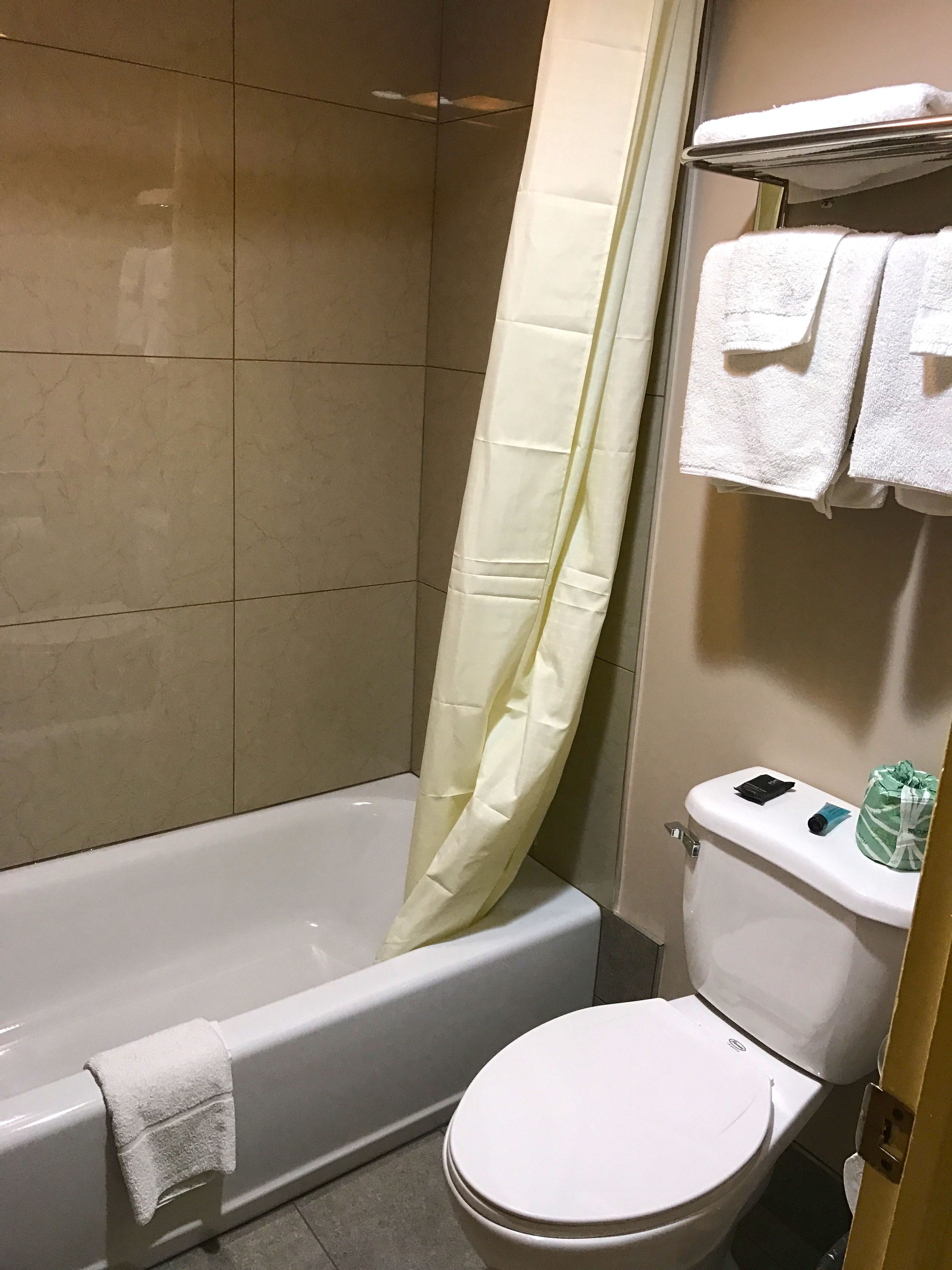 Un baño con bañera, inodoro y cortina de ducha.