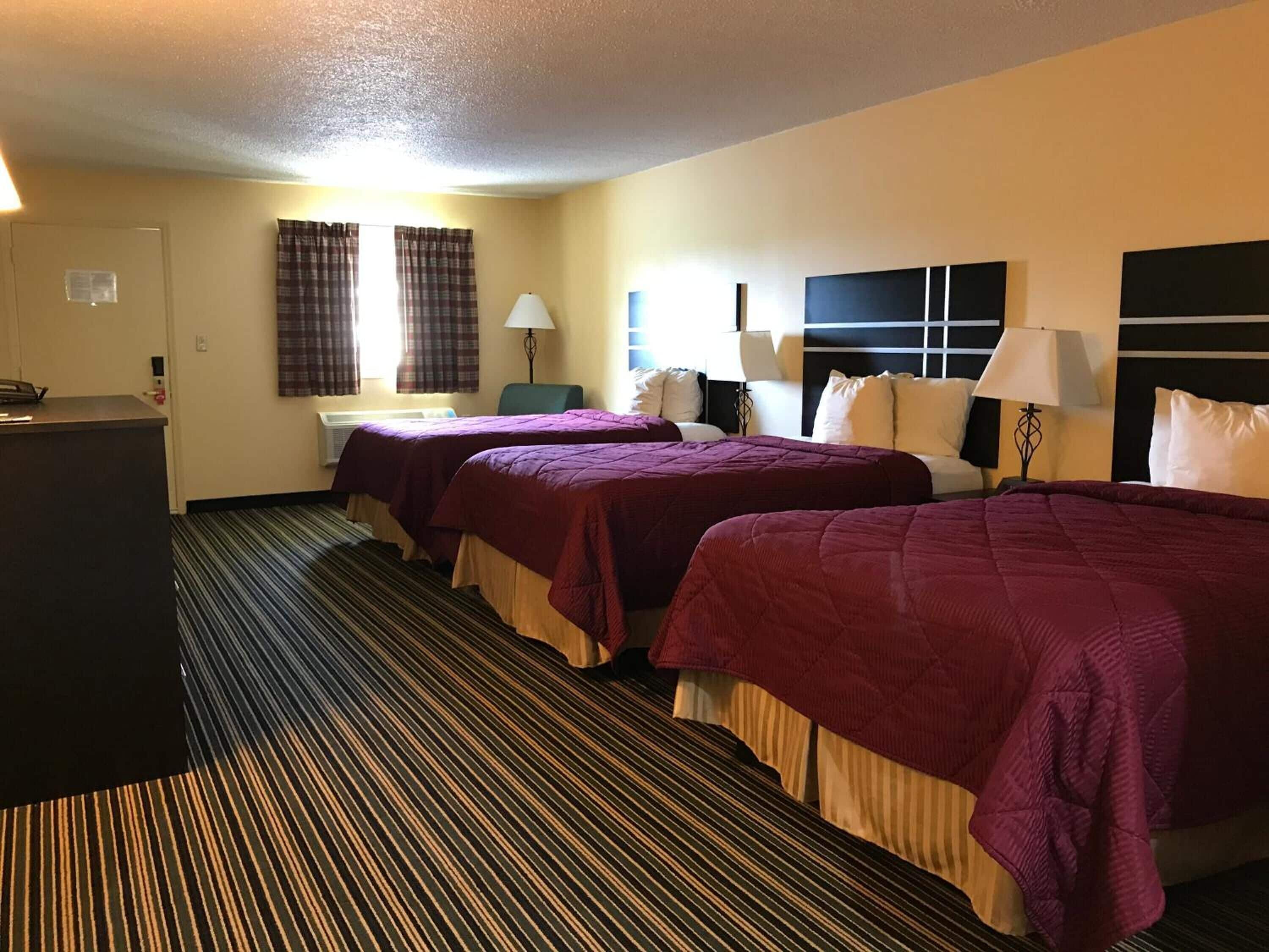 A hotel room with two beds, a desk, and a reception area.