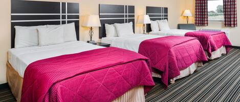 Habitación de hotel con tres camas, cada una con sábanas blancas y colchas rosas. Se observan mesitas de noche con lámparas, una ventana con cortinas y suelo cubierto de alfombra.