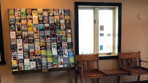 A wall of postcards and a wooden bench by a window.