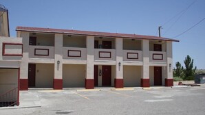 A multi-story motel with a red roof and beige walls, featuring a central entrance and multiple balconies. - Fabens Inn Motel (Fabens)