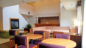 A hotel lobby with a seating area, a reception desk, and a large window. - Budget Host Inn (Allegan)