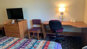 Une chambre d’hôtel avec un lit, un bureau en bois, un ordinateur, une chaise, une télévision et une lampe de chevet.