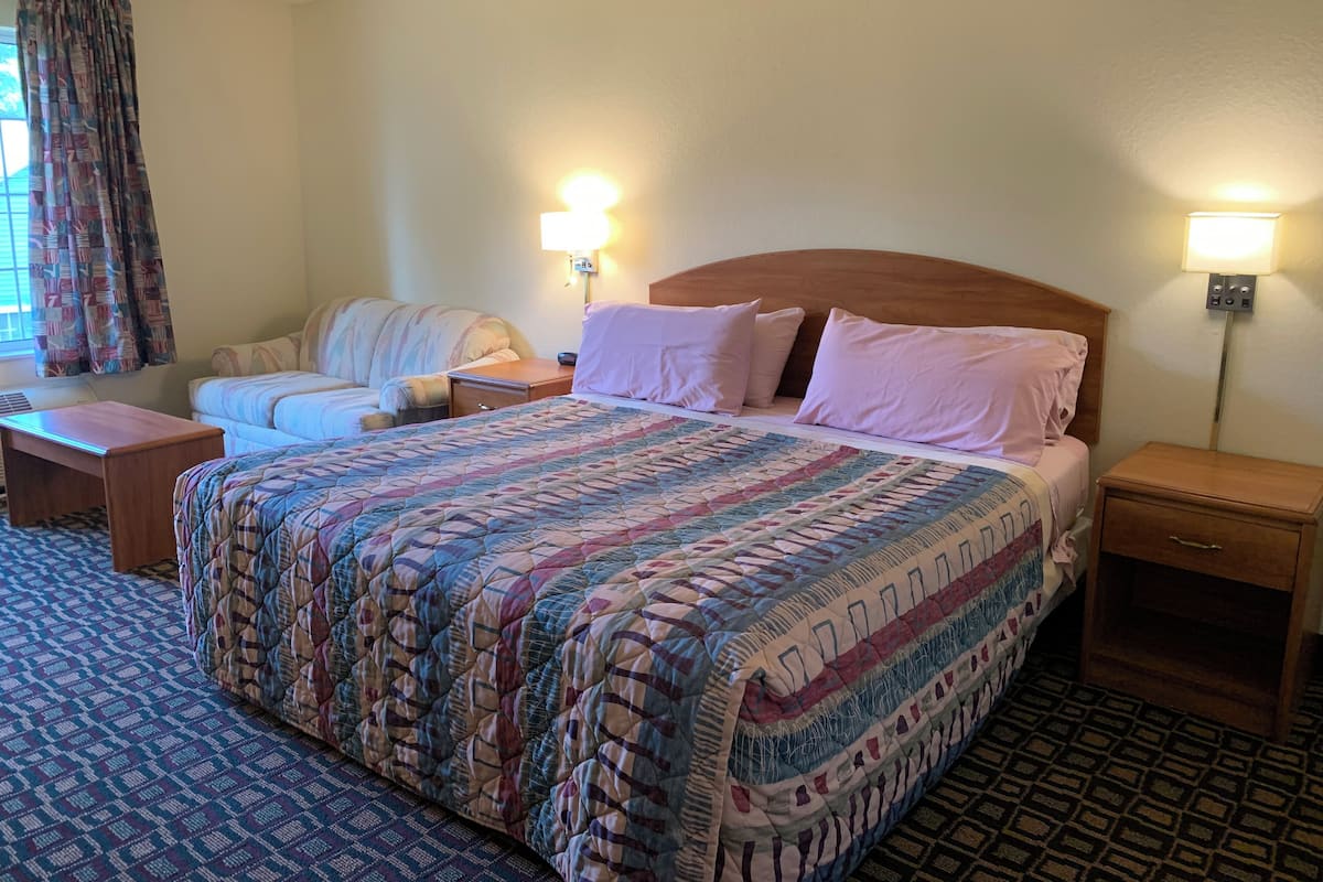 Une chambre d’hôtel avec un grand lit, un canapé, une table de chevet et une lampe.