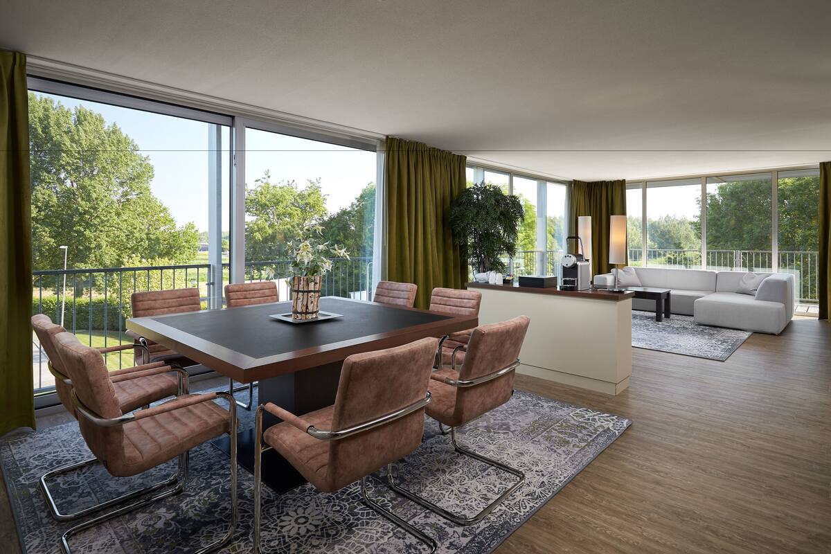 A modern living room with a dining area, large windows, and a balcony.