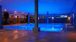 A large indoor swimming pool with a tiled floor, surrounded by walls and pillars, and a ceiling with recessed lighting. - Van der Valk Hotel ARA (Zwijndrecht)