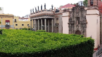 Un patio con un seto cuidado, una estatua y un edificio de arquitectura clásica.