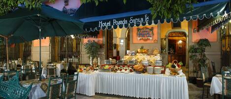 A buffet setup at Hotel Posada Santa Fé with tables covered in white tablecloths and a variety of food items.