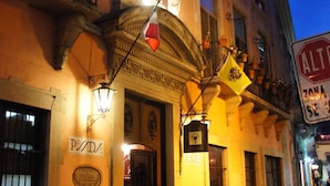 Un edificio histórico con arquitectura ornamentada, un cartel que dice "POSADA" y un farol.