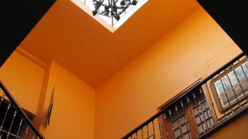 Una escalera con barandales de metal ornamentados y un tragaluz arriba.
