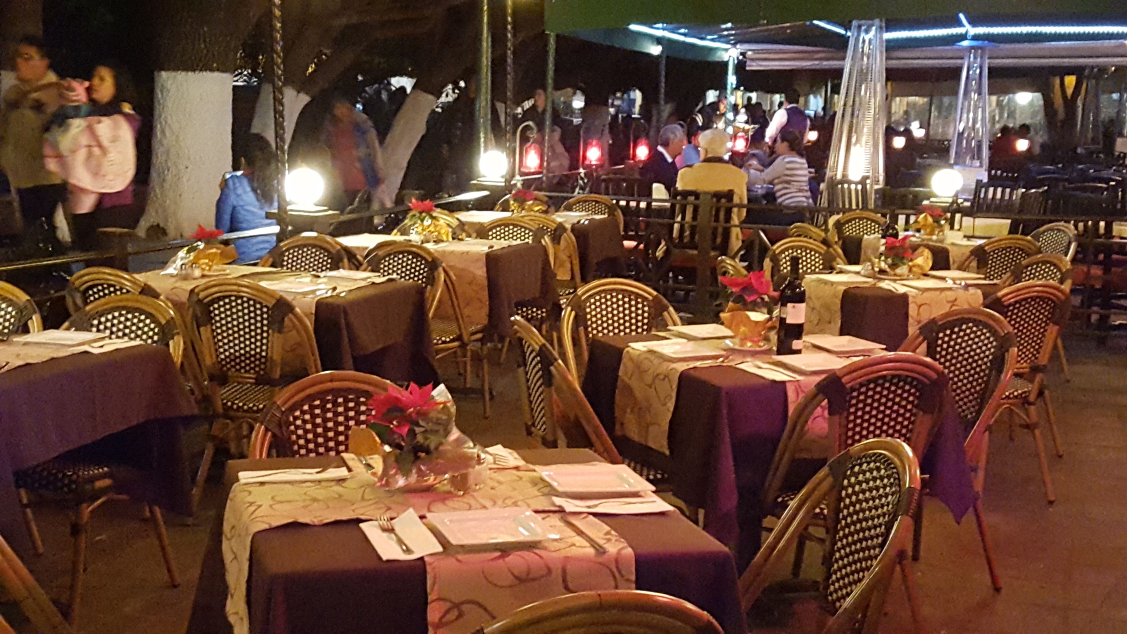 A restaurant with tables set for dining, wicker chairs, and a warm ambiance.