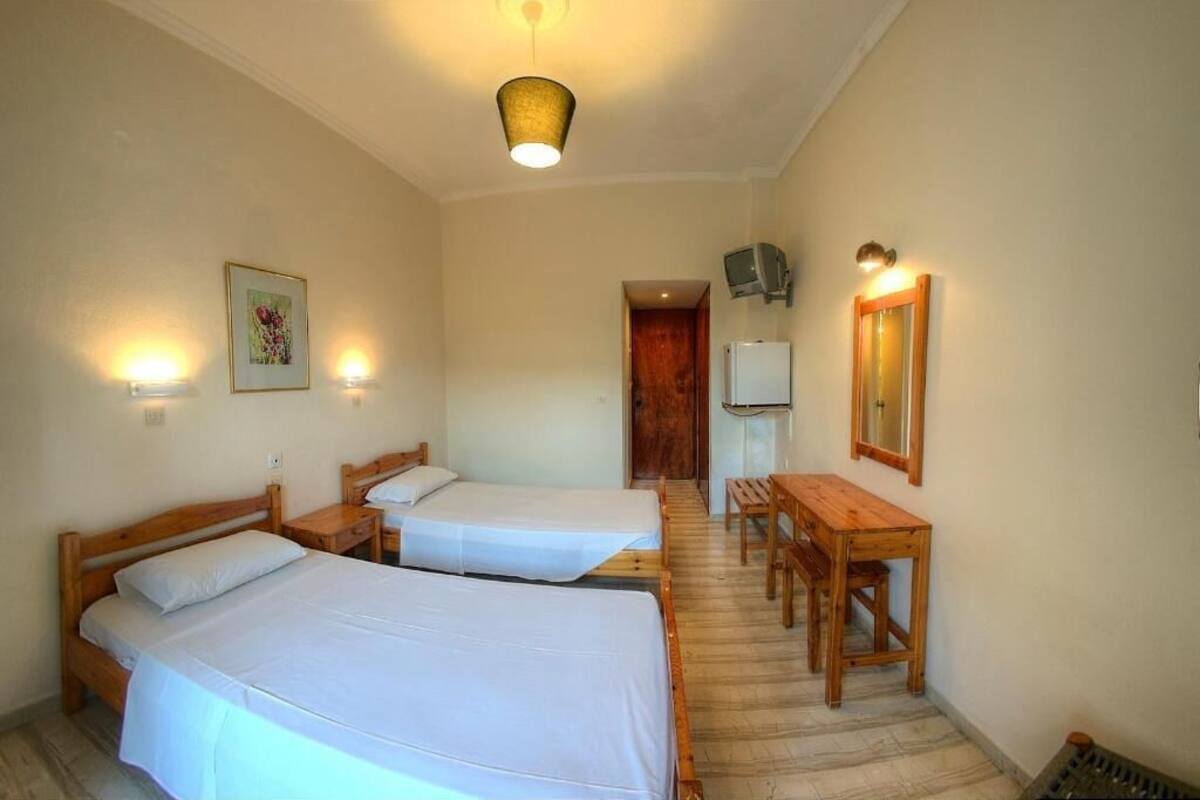 A room with two beds, a wooden desk, a television, and a mirror.