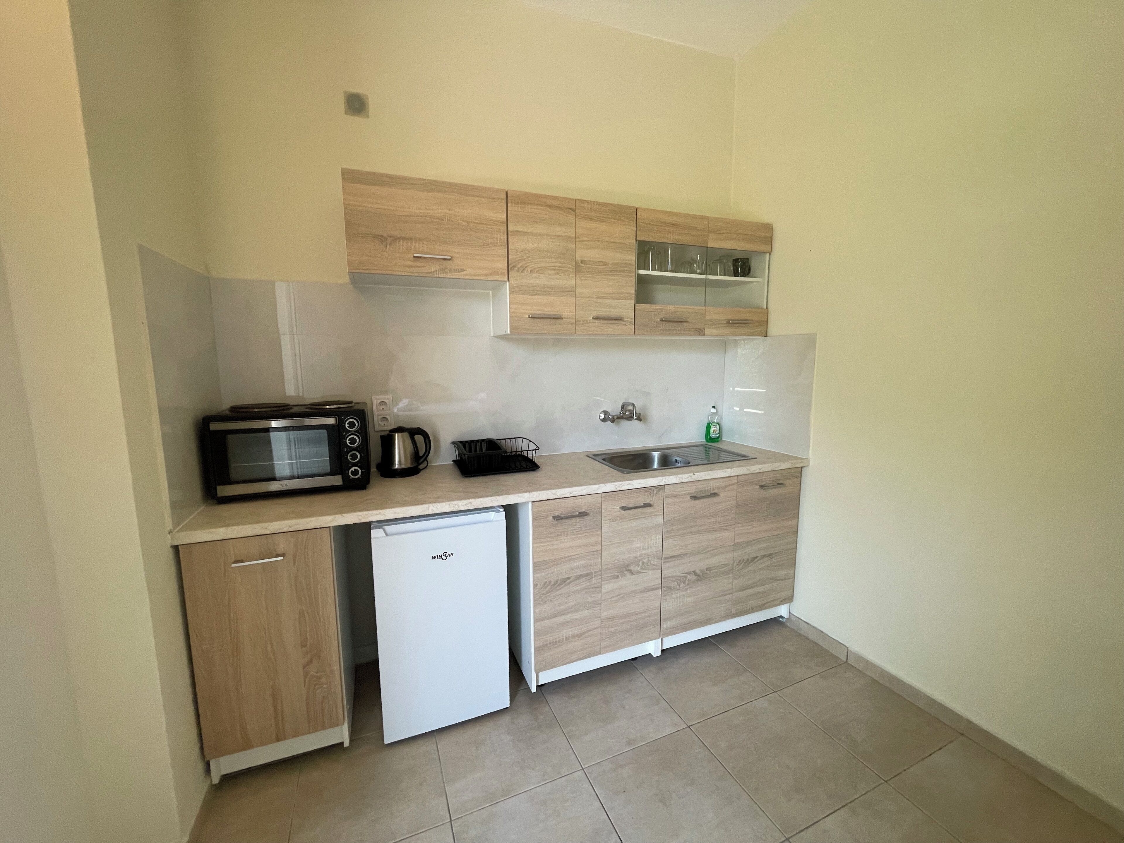 A compact kitchen with a built-in microwave, a coffee maker, a sink, and a dishwasher.