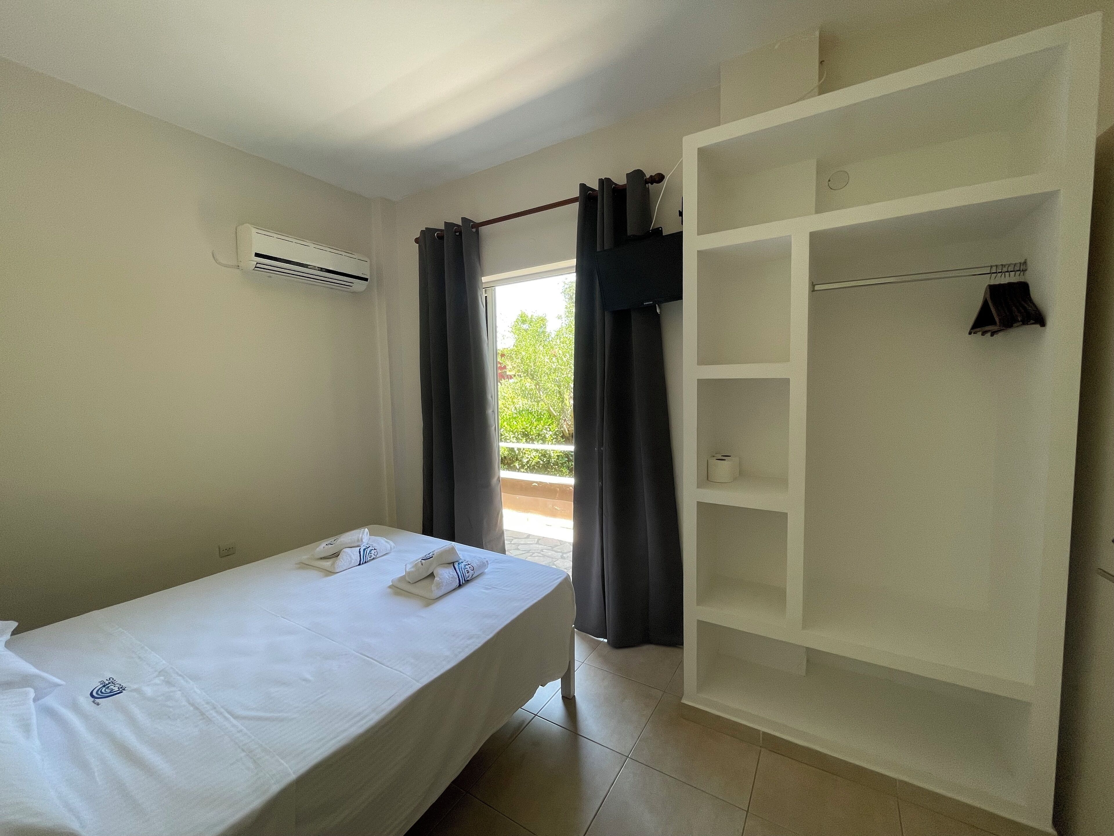 Ein Hotelzimmer mit einem Einzelbett, einem Kleiderschrank und einer Klimaanlage.