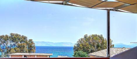 A balcony with a view of the sea and mountains.