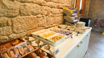 Buffet amb diferents plats i una paret de pedra al fons.