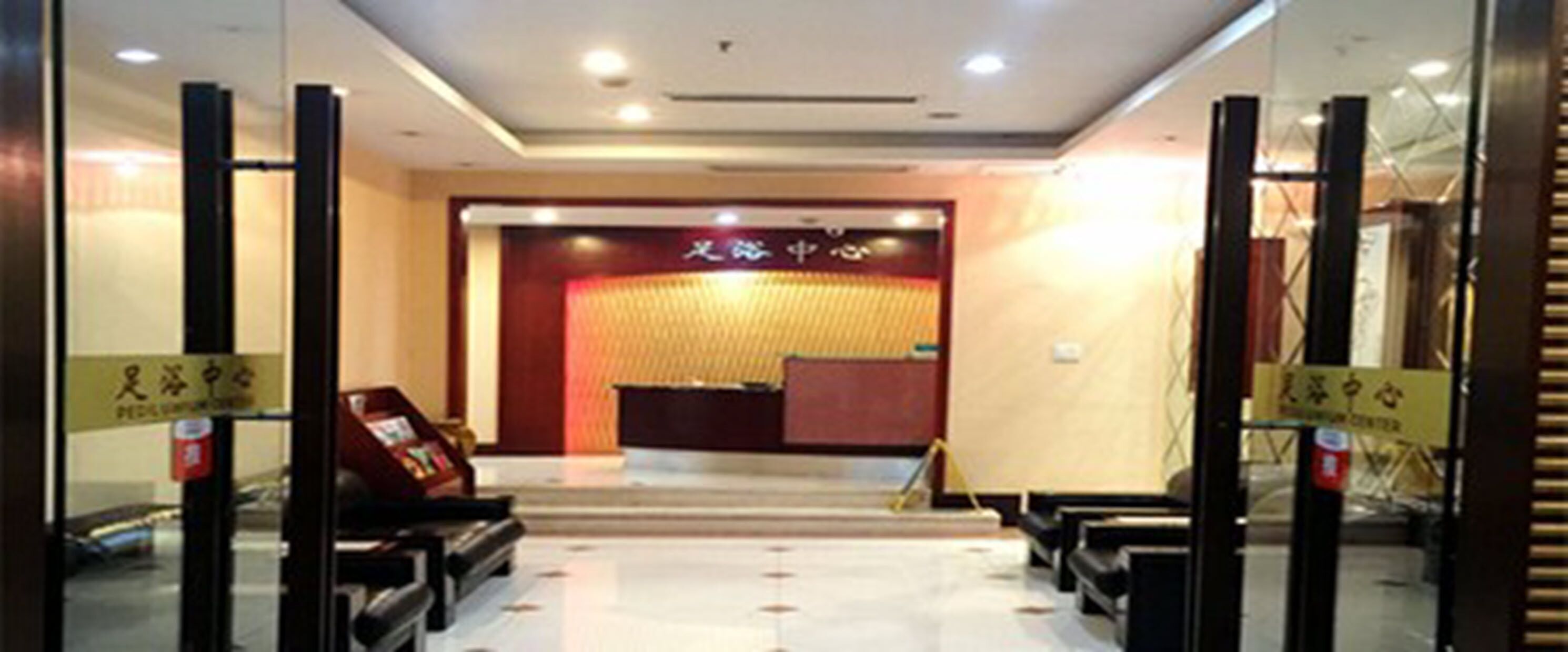 A hotel reception area with a reception desk, a seating area with chairs, and a sign indicating the location of the reception.