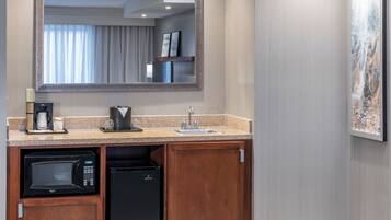 A compact kitchen with a built-in microwave, coffee maker, and refrigerator.
