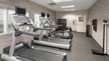 Une salle de sport équipée de tapis de course, d’un vélo d’appartement et d’un banc de musculation.