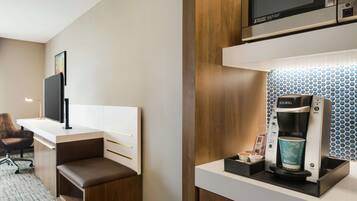 Habitación de hotel compacta con kitchenette, televisión de pantalla plana, zona de estar y cafetera Keurig.