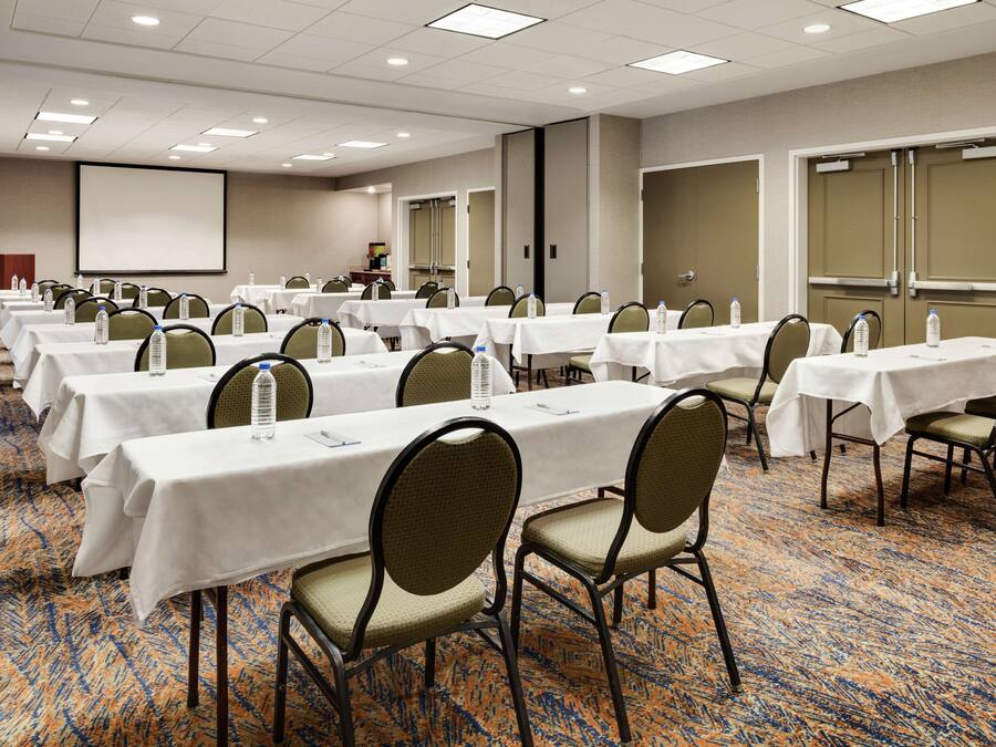 A conference room with multiple tables, chairs, and a projector screen.
