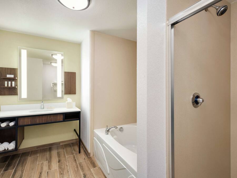 A modern bathroom with a large mirror, a bathtub, and a shower.