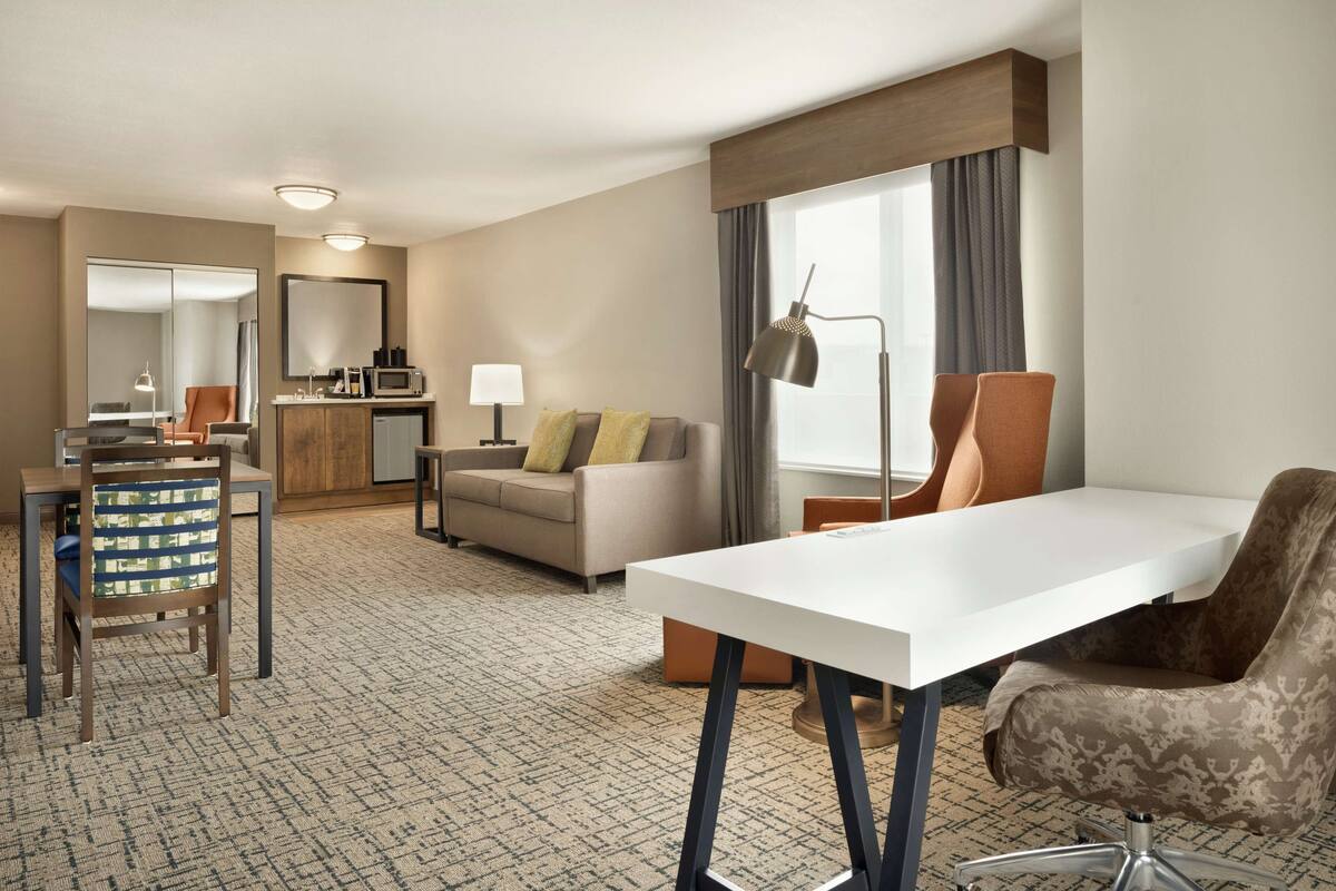 Ein Hotelzimmer mit Essbereich, einer Couch, einem Schreibtisch und einem Stuhl.