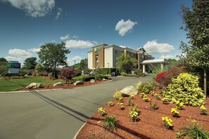 Ein Holiday Inn Express Hotel mit begrüntem Zufahrtsweg und Blumenbeeten.