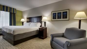 Una habitación de hotel con una cama, dos mesitas de noche con lámparas, una silla y una pared decorada con cuadros.