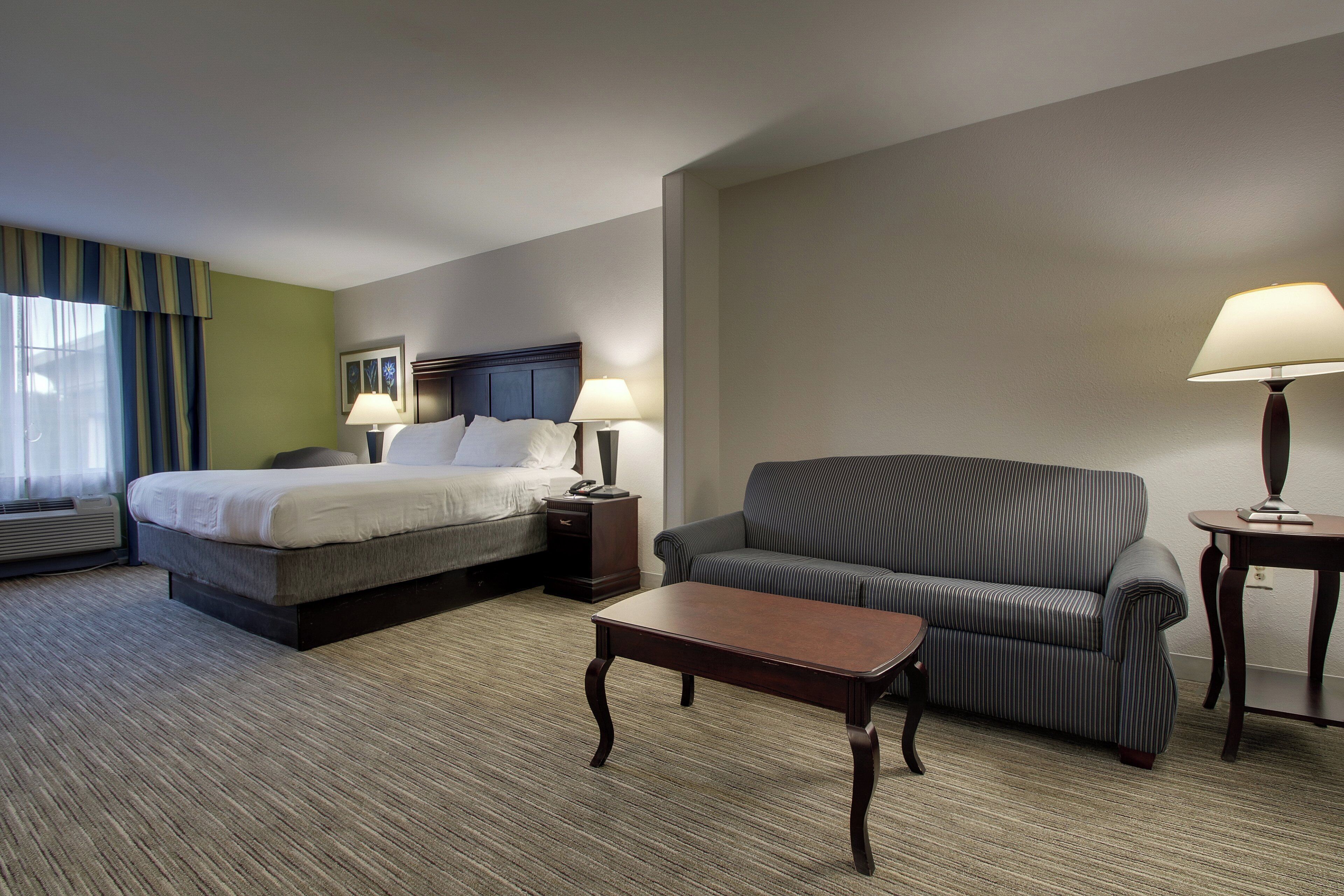 Una habitación de hotel con una cama, un sofá, una mesita y dos lámparas de noche.