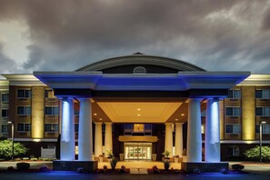 Ein Hotel mit Eingangsbereich, überdachtem Gang, Säulen und blauem Himmel.
