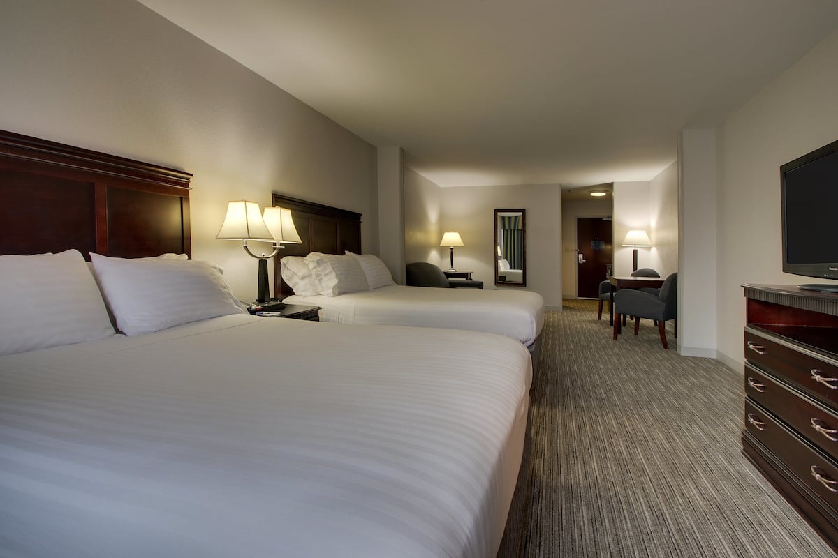A hotel room with two beds, a TV, a desk, and a chair.