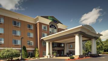 A hotel with a covered entrance, multiple windows, and a clear sky.