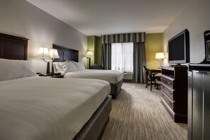 Une chambre d’hôtel avec deux lits, un bureau avec un ordinateur, une télévision et une fenêtre avec des rideaux.