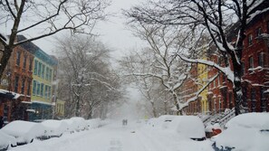 Une rue enneigée, bordée de bâtiments des deux côtés.