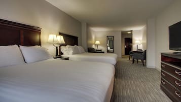A hotel room with two beds, a desk, a chair, a TV, and a dresser.